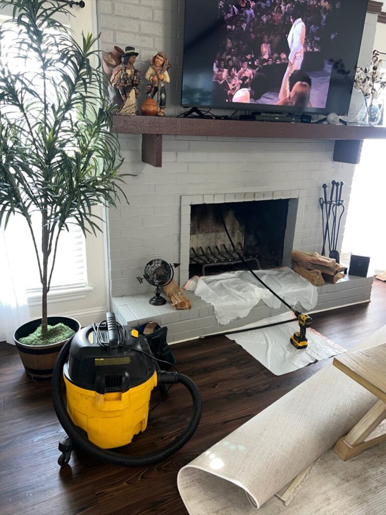Chimney cleaning in progress with drop cloth protecting the hearth
