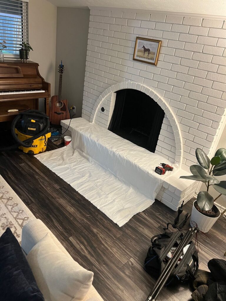 White brick fireplace prepped with drop cloths before service in a DFW home